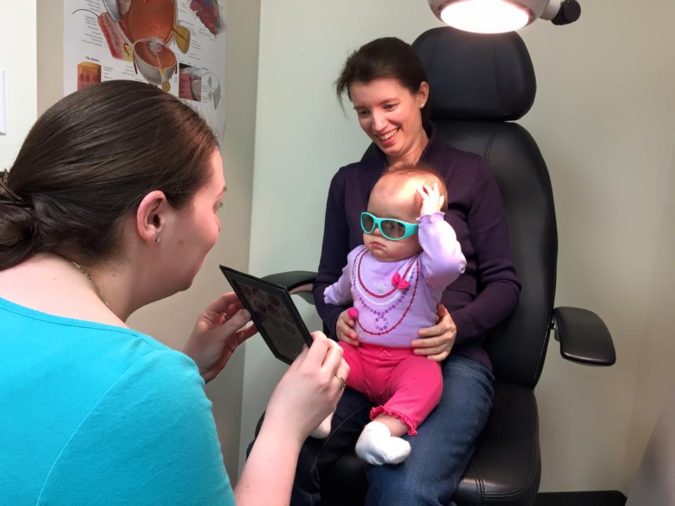 Baby being held by mother while optometrist is testing 3D vision